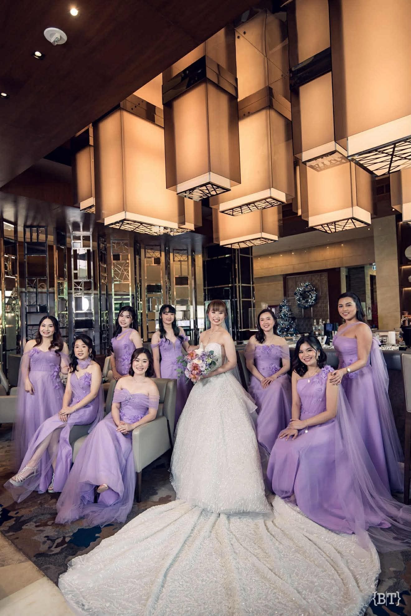 Bride with her coordinated entourage in matching lavender gowns, posed together at the wedding venue.