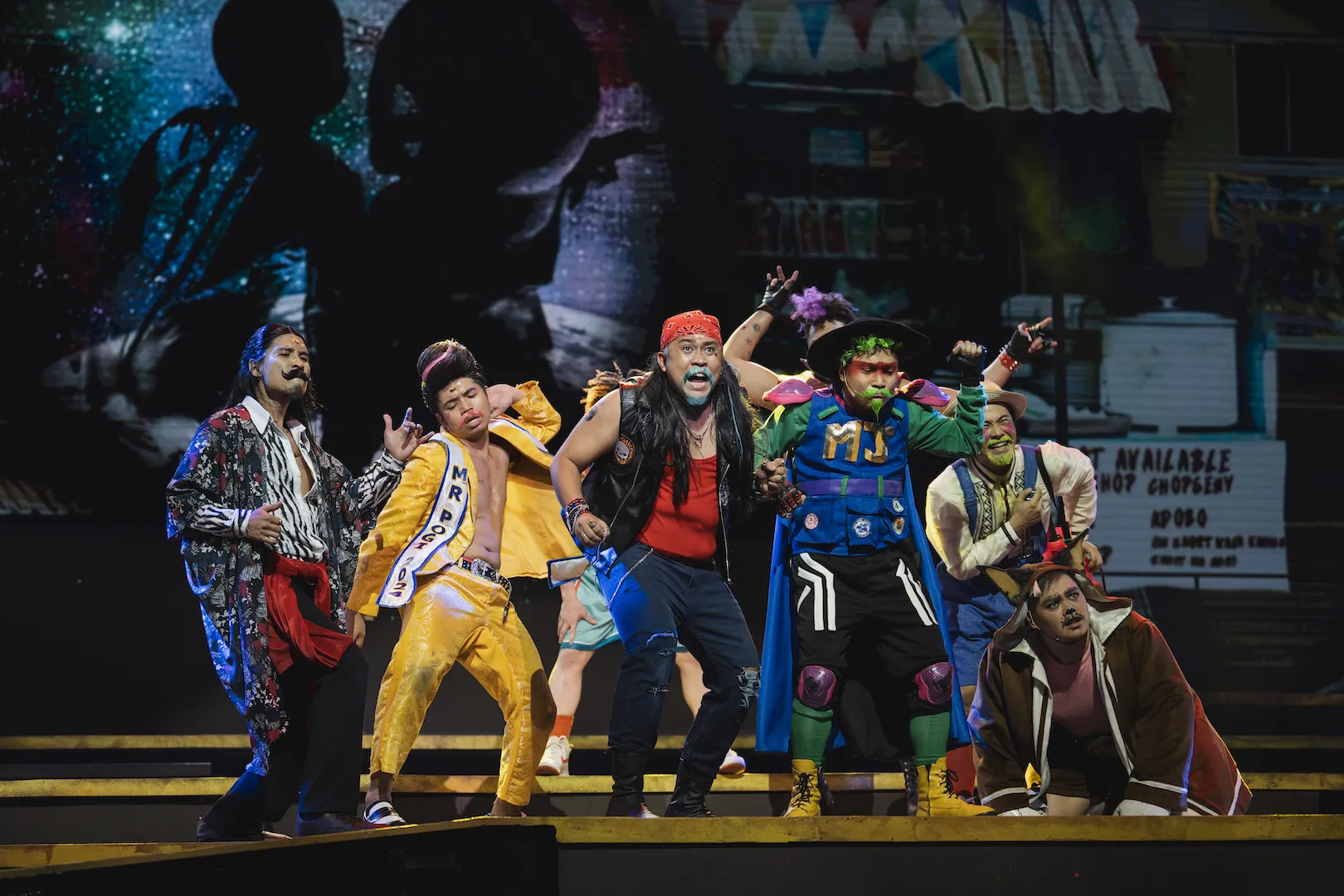 Colorful character makeup and costumes during a comedic musical performance number.